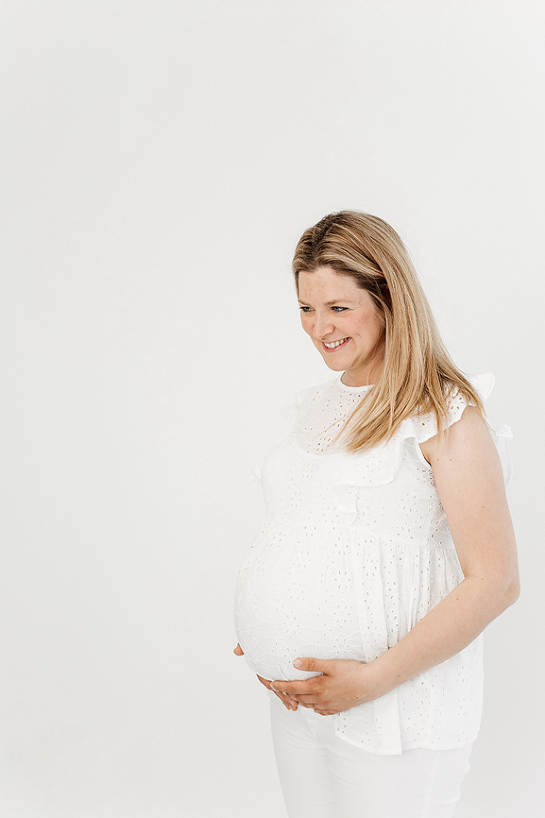 Babybauchshooting Bielefeld: Schwangere schaut seitlich auf ihren Sohn und grinst ihn zufrieden an